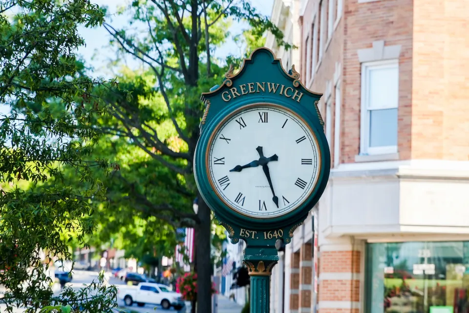 Close-up of green ornate clock with Greenwich written in gold on street in downtown Greenwich, Connecticut.
